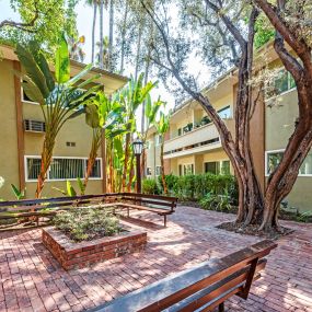 courtyard with benches and trees in front of an apartment building