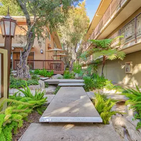 a walkway between two buildings with trees and plants