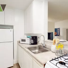 a white kitchen with a stove sink and refrigerator