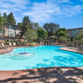 a resort style pool with chairs and a building in the background