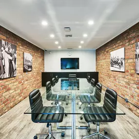 a conference room with a glass table and chairs and an exposed brick wall