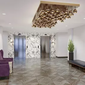 a rendering of a lobby with purple chairs and a gold chandelier