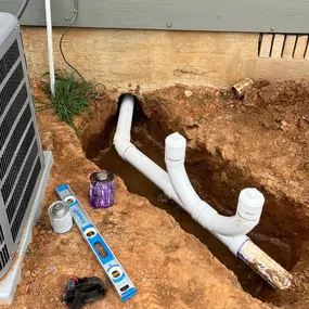 A pipe break repair next to an AC condenser. The pipe break has been excavated and replaced