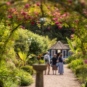 Visitors enjoy a tranquil walk under rose-covered archways at Sledmere House Gardens, a perfect spot for nature lovers to explore its floral beauty.