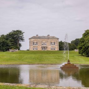 A stunning view of Sledmere House with its beautiful fountain and reflecting pond, offering a tranquil and picturesque landscape within the estate grounds.