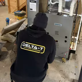 Delta T Heating & Cooling technician performing a furnace repair in a Grand Rapids, MI basement. Ensuring reliable heating with expert HVAC service. Serving Northview, Creston, Rockford, and surrounding areas.