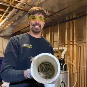 Delta T Heating & Cooling technician Brandon VanDyke removing a bird's nest from a furnace flue pipe in Grand Rapids, MI. A blocked vent can cause serious heating system failures—don’t let unexpected issues leave you in the cold! We provide fast, reliable furnace repairs in Northview, Creston, Rockford, and surrounding areas.