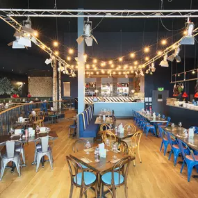 Contemporary Italian dining at Zizzi Bexleyheath with bright, welcoming interiors. Fairy lights light up the ceiling, whilst exotic art walls create a captivating backdrop, energising the dining experience.