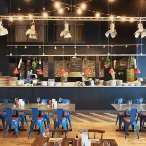 Contemporary Italian dining at Zizzi Bexleyheath with bright, welcoming interiors. Fairy lights light up the ceiling, whilst exotic art walls create a captivating backdrop, energising the dining experience.