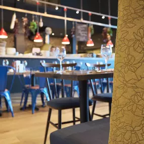 Contemporary Italian dining at Zizzi Bexleyheath with bright, welcoming interiors. Fairy lights light up the ceiling, whilst exotic art walls create a captivating backdrop, energising the dining experience.