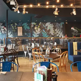 Contemporary Italian dining at Zizzi Bexleyheath with bright, welcoming interiors. Fairy lights light up the ceiling, whilst exotic art walls create a captivating backdrop, energising the dining experience.