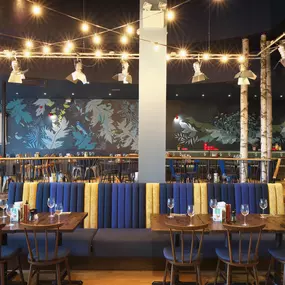 Contemporary Italian dining at Zizzi Bexleyheath with bright, welcoming interiors. Fairy lights light up the ceiling, whilst exotic art walls create a captivating backdrop, energising the dining experience.