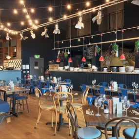 Contemporary Italian dining at Zizzi Bexleyheath with bright, welcoming interiors. Fairy lights light up the ceiling, whilst exotic art walls create a captivating backdrop, energising the dining experience.