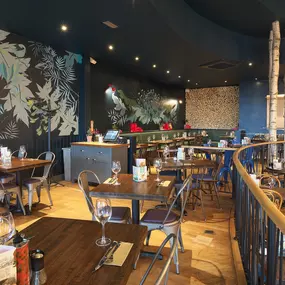 Contemporary Italian dining at Zizzi Bexleyheath with bright, welcoming interiors. Fairy lights light up the ceiling, whilst exotic art walls create a captivating backdrop, energising the dining experience.