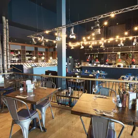Contemporary Italian dining at Zizzi Bexleyheath with bright, welcoming interiors. Fairy lights light up the ceiling, whilst exotic art walls create a captivating backdrop, energising the dining experience.
