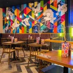Zizzi Metro Centre, lively interior with vibrant foliage, neon lighting and bold seating.