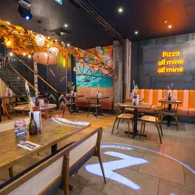Zizzi Metro Centre, lively interior with vibrant foliage, neon lighting and bold seating.