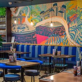 Zizzi Metro Centre, lively interior with vibrant foliage, neon lighting and bold seating.