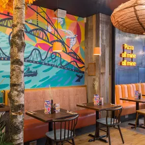 Zizzi Metro Centre, lively interior with vibrant foliage, neon lighting and bold seating.