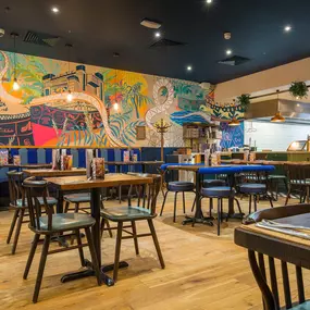 Zizzi Metro Centre, lively interior with vibrant foliage, neon lighting and bold seating.