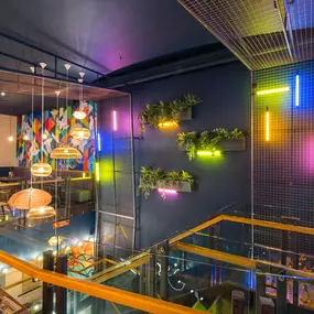 Zizzi Metro Centre, lively interior with vibrant foliage, neon lighting and bold seating.