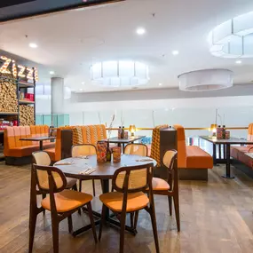 Zizzi Metro Centre, lively interior with vibrant foliage, neon lighting and bold seating.