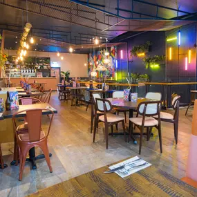 Zizzi Metro Centre, lively interior with vibrant foliage, neon lighting and bold seating.