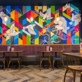 Zizzi Metro Centre, lively interior with vibrant foliage, neon lighting and bold seating.