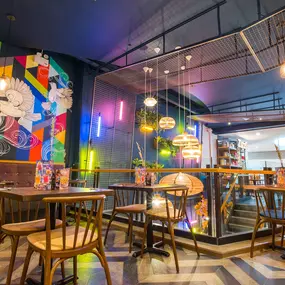 Zizzi Metro Centre, lively interior with vibrant foliage, neon lighting and bold seating.