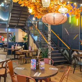 Zizzi Metro Centre, lively interior with vibrant foliage, neon lighting and bold seating.