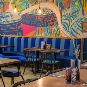Zizzi Metro Centre, lively interior with vibrant foliage, neon lighting and bold seating.