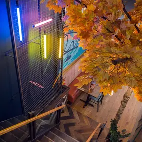 Zizzi Metro Centre, lively interior with vibrant foliage, neon lighting and bold seating.