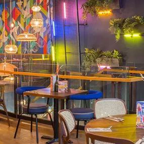 Zizzi Metro Centre, lively interior with vibrant foliage, neon lighting and bold seating.