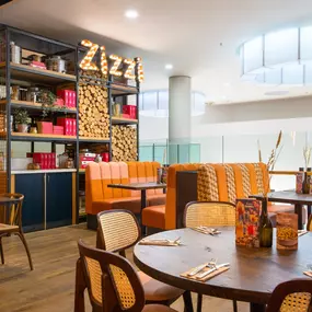 Zizzi Metro Centre, lively interior with vibrant foliage, neon lighting and bold seating.