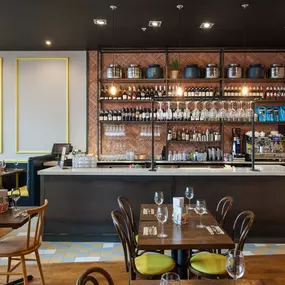 Interior view of Zizzi Liverpool One, featuring a bright, open dining space with colourful seating, mural art and tree decor.