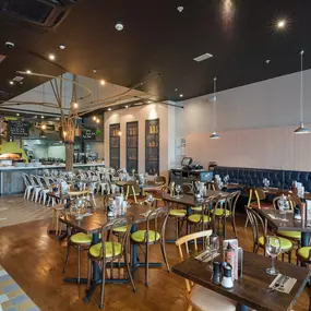 Interior view of Zizzi Liverpool One, featuring a bright, open dining space with colourful seating, mural art and tree decor.