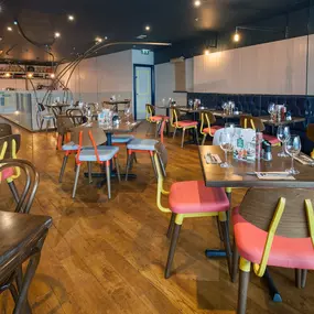 Interior view of Zizzi Liverpool One, featuring a bright, open dining space with colourful seating, mural art and tree decor.