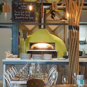 Interior view of Zizzi Liverpool One, featuring a bright, open dining space with colourful seating, mural art and tree decor.
