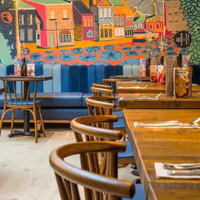 Zizzi Farnham, cozy interior with vibrant murals and hanging orange foliage.