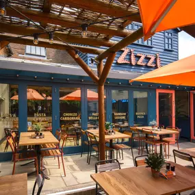Zizzi Farnham, tucked-away courtyard with covered outdoor terrace and glowing sign.