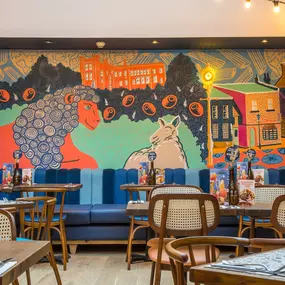 Zizzi Farnham, cozy interior with vibrant murals and hanging orange foliage.