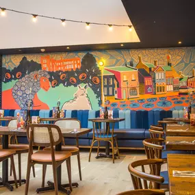 Zizzi Farnham, cozy interior with vibrant murals and hanging orange foliage.
