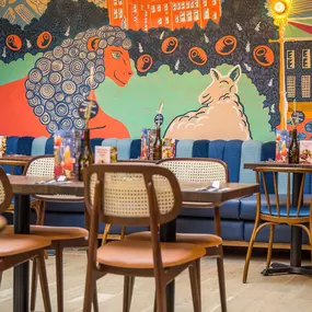 Zizzi Farnham, cozy interior with vibrant murals and hanging orange foliage.