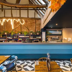 Zizzi Farnham, cozy interior with vibrant murals and hanging orange foliage.