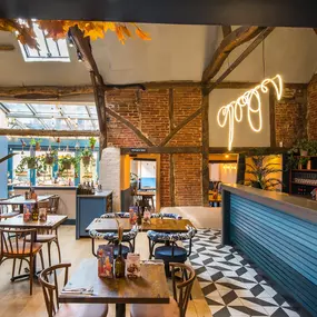 Zizzi Farnham, cozy interior with vibrant murals and hanging orange foliage.