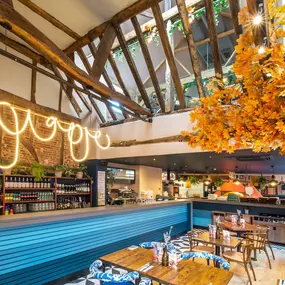 Zizzi Farnham, cozy interior with vibrant murals and hanging orange foliage.