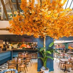 Zizzi Farnham, cozy interior with vibrant murals and hanging orange foliage.