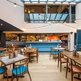 Zizzi Farnham, cozy interior with vibrant murals and hanging orange foliage.