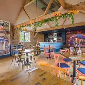 Zizzi Farnham, cozy interior with vibrant murals and hanging orange foliage.