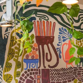 Zizzi Farnham, cozy interior with vibrant murals and hanging orange foliage.